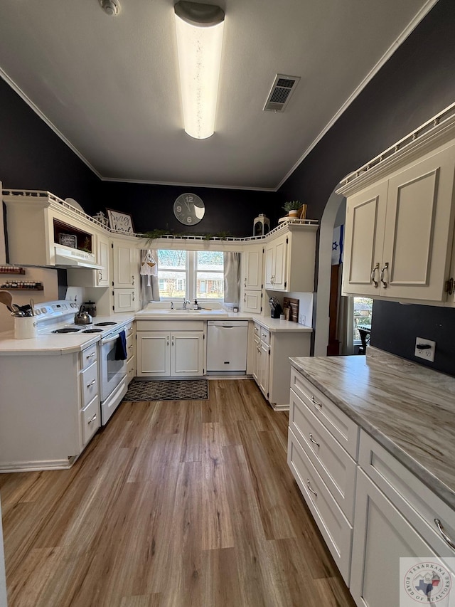 kitchen with arched walkways, white appliances, visible vents, light wood finished floors, and crown molding