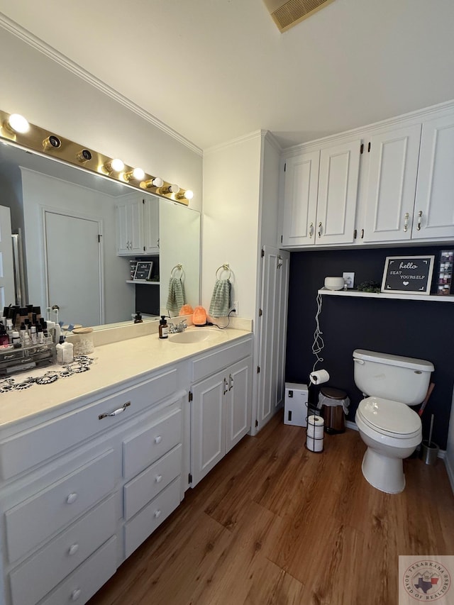 bathroom featuring visible vents, toilet, wood finished floors, crown molding, and vanity