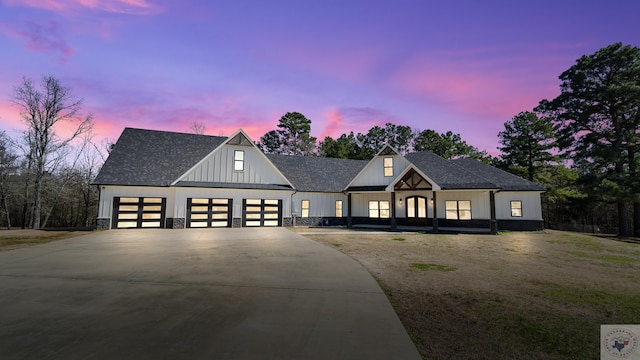 modern farmhouse style home featuring driveway, stone siding, a shingled roof, and board and batten siding