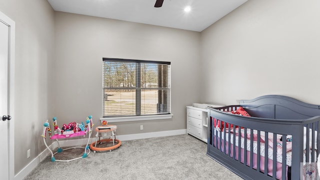 bedroom with a crib, carpet, a ceiling fan, and baseboards