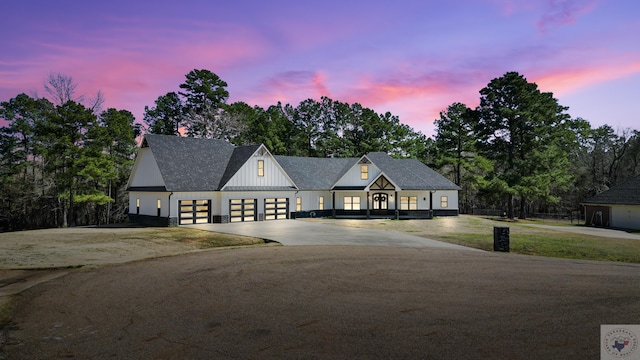 modern inspired farmhouse featuring concrete driveway, board and batten siding, an attached garage, and roof with shingles