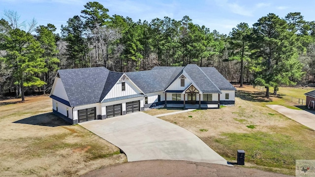 view of front of home featuring roof with shingles, concrete driveway, an attached garage, board and batten siding, and a front lawn