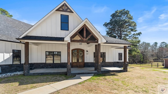 modern farmhouse style home with roof with shingles, french doors, board and batten siding, and a front yard