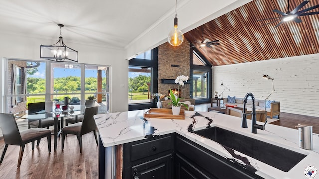 1142 Oakridge Dr, Texarkana, TX 75503 - kitchen with dark cabinetry, light stone countertops, wood finished floors, a chandelier, and hanging light fixtures