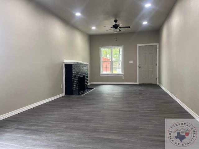 unfurnished living room featuring ceiling fan, dark wood-type flooring, and a fireplace