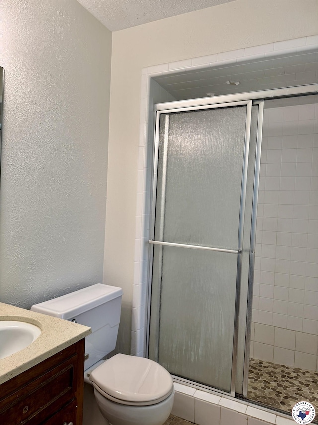 4211 Lotus Dr, Texarkana, TX 75503 - bathroom with a textured wall, a shower stall, vanity, and toilet