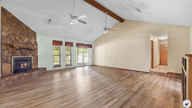 1135 Cook Rd, Texarkana, AR 71854 - unfurnished living room featuring a stone fireplace, beamed ceiling, wood finished floors, ceiling fan, and high vaulted ceiling
