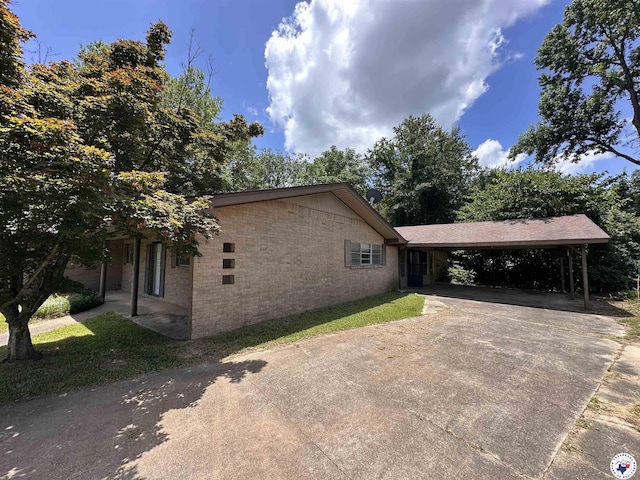 216 W Pioneer St, Wake Village, TX 75501 - view of property exterior with concrete driveway, brick siding, and an attached carport