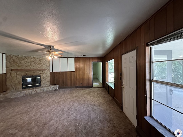 216 W Pioneer St, Wake Village, TX 75501 - unfurnished living room featuring a ceiling fan, wood walls, a textured ceiling, carpet, and a fireplace