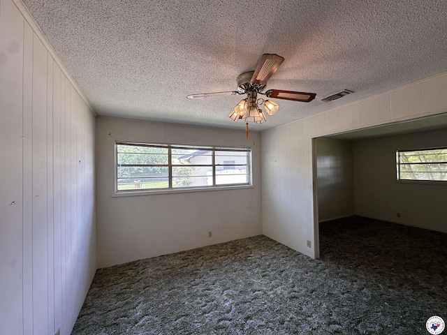 216 W Pioneer St, Wake Village, TX 75501 - carpeted empty room featuring healthy amount of natural light, a textured ceiling, wood walls, and a ceiling fan