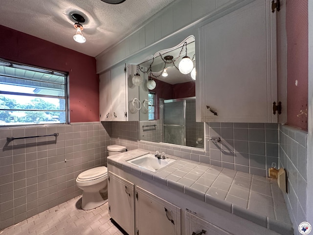 216 W Pioneer St, Wake Village, TX 75501 - full bath with a stall shower, vanity, tile walls, a textured ceiling, and a wainscoted wall