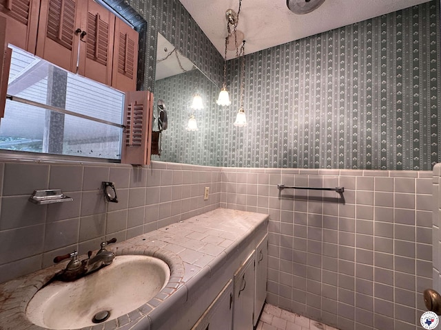 216 W Pioneer St, Wake Village, TX 75501 - bathroom featuring wallpapered walls, tile walls, vanity, wainscoting, and a textured ceiling