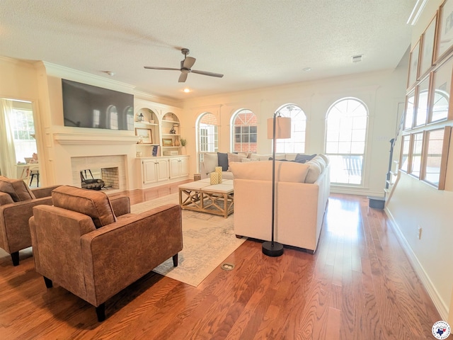 3815 Wyatt Ln, Texarkana, TX 75503 - living area with a textured ceiling, wood finished floors, ceiling fan, ornamental molding, and a fireplace