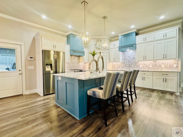 kitchen with hanging light fixtures, wood finished floors, stainless steel refrigerator with ice dispenser, and a kitchen bar