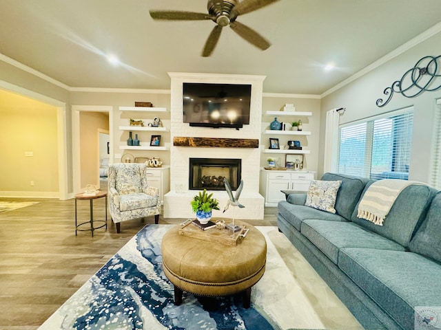 living room with a brick fireplace, baseboards, built in features, ornamental molding, and wood finished floors