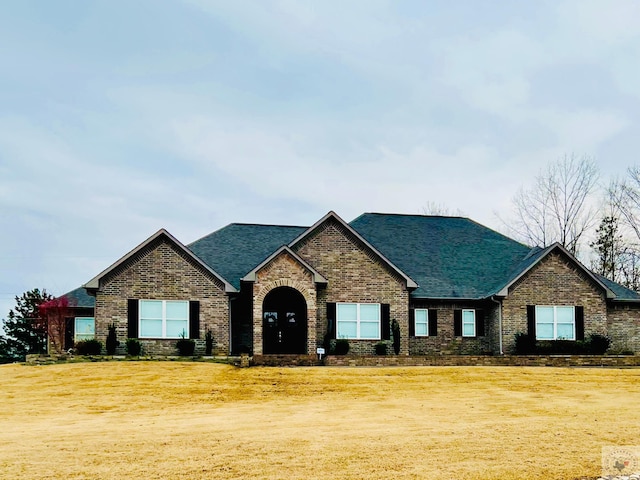 view of front facade featuring brick siding, a front lawn, and roof with shingles