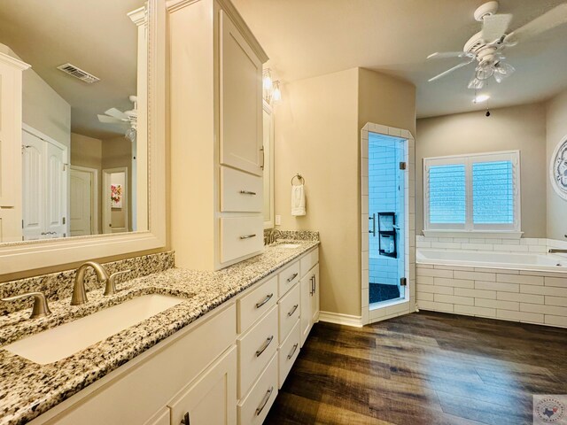 bathroom with wood finished floors, visible vents, ceiling fan, a sink, and a garden tub