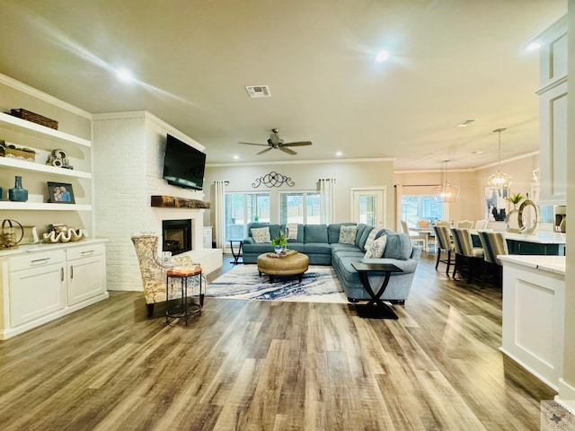 living room with plenty of natural light, a fireplace, light wood-type flooring, and ornamental molding