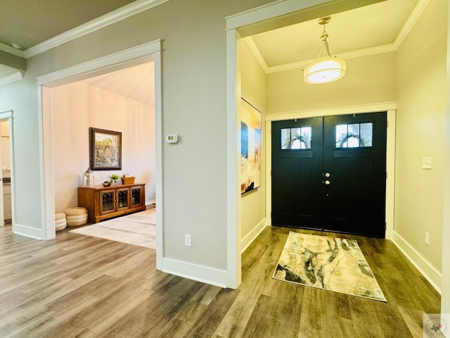 foyer entrance featuring wood finished floors, baseboards, and ornamental molding