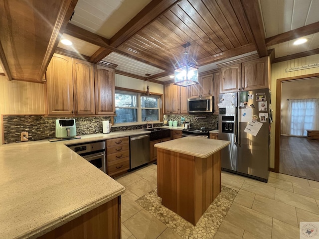 kitchen with hanging light fixtures, a kitchen island, stainless steel appliances, beam ceiling, and decorative backsplash