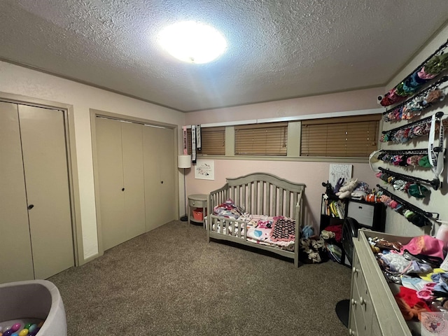 carpeted bedroom featuring two closets and a textured ceiling