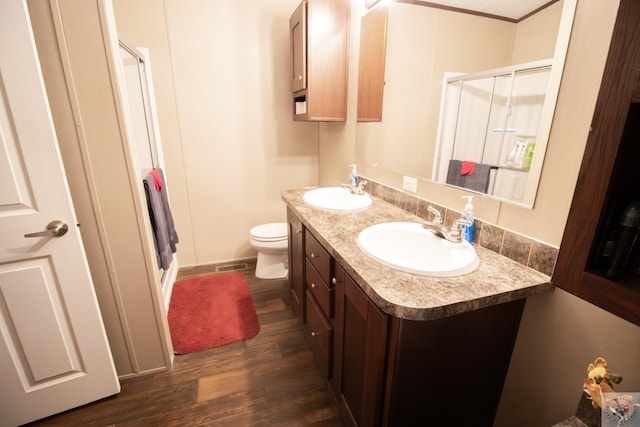 bathroom with a sink, wood finished floors, a stall shower, and double vanity