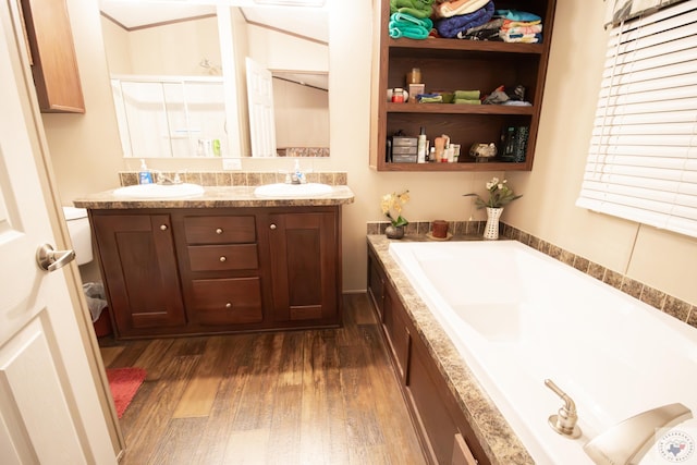 full bath with double vanity, a bath, wood finished floors, and a sink