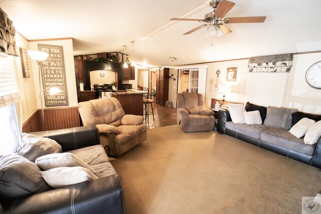 living room featuring dark carpet, lofted ceiling, ornamental molding, and a ceiling fan