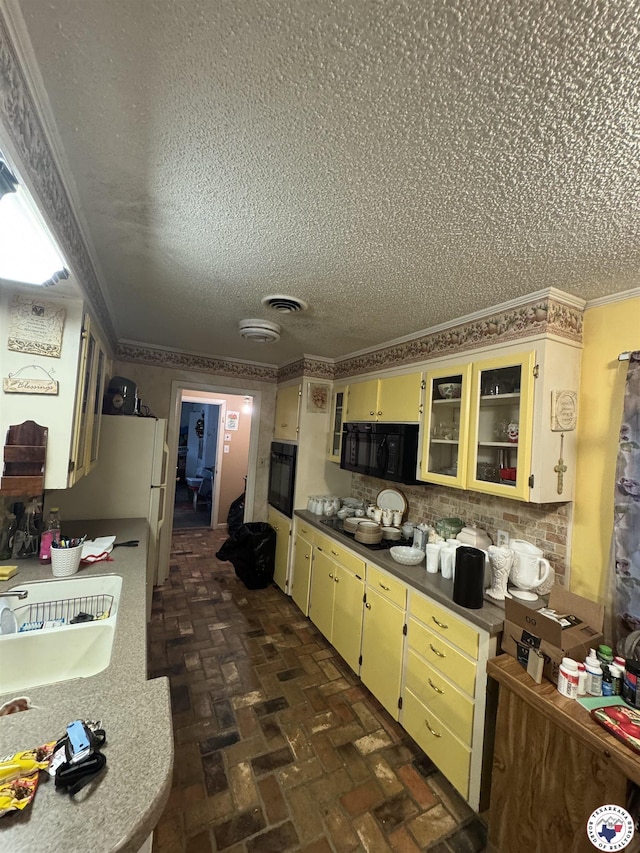 3811 Potomac Ave, Texarkana, TX 75501 - kitchen with black appliances, cream cabinets, a textured ceiling, brick flooring, and dark countertops