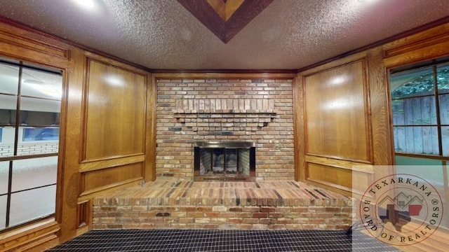 living area featuring wood walls, a fireplace, and a textured ceiling