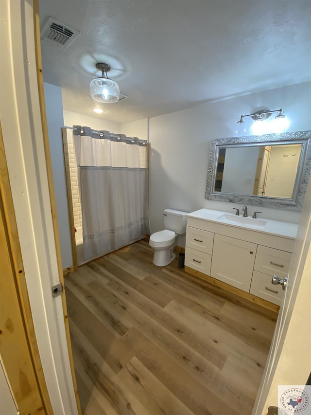 bathroom featuring vanity, hardwood / wood-style flooring, toilet, and a shower with curtain