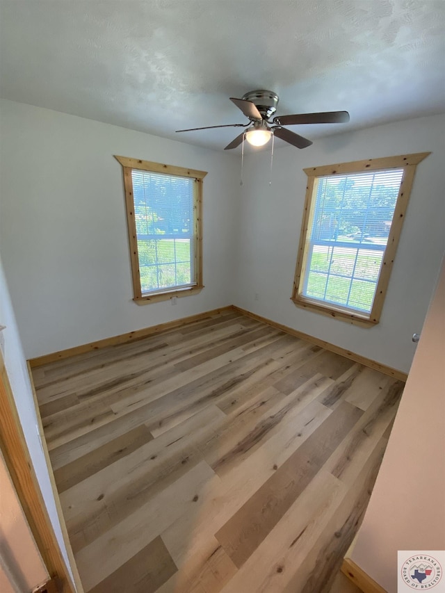 empty room with light hardwood / wood-style floors, plenty of natural light, and ceiling fan