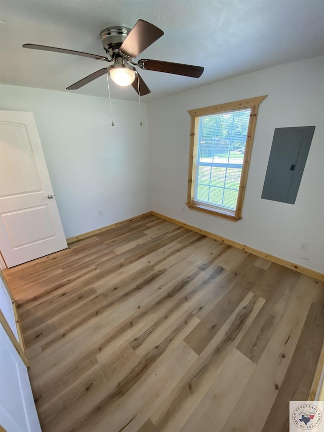 unfurnished room featuring electric panel and light hardwood / wood-style floors