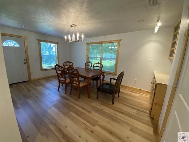 dining area featuring light hardwood / wood-style flooring and an inviting chandelier