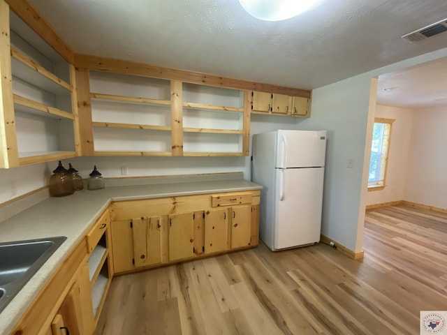 kitchen featuring light wood-type flooring, light brown cabinets, white refrigerator, and sink