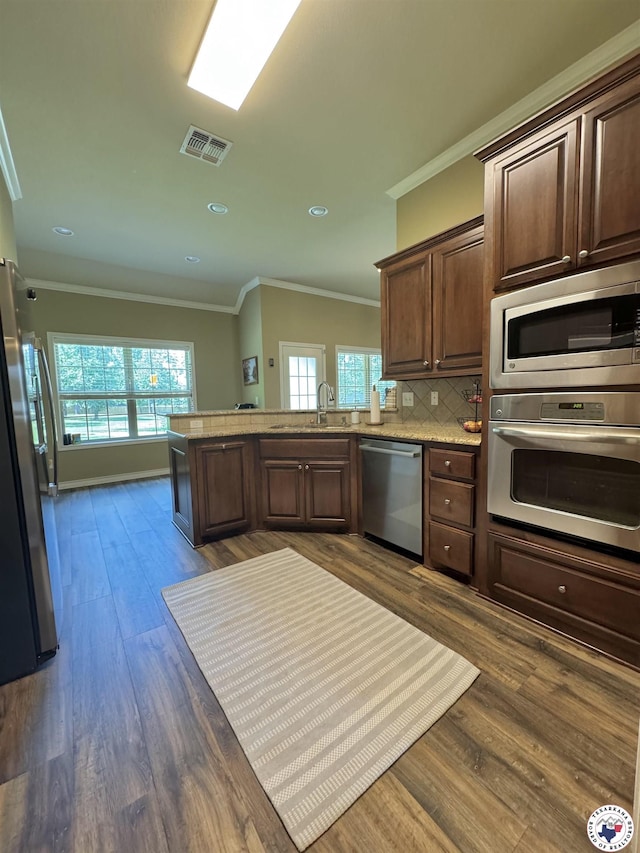 22 Heritage Blvd, Texarkana, TX 75501 - kitchen with ornamental molding, stainless steel appliances, a peninsula, healthy amount of natural light, and dark wood-style flooring