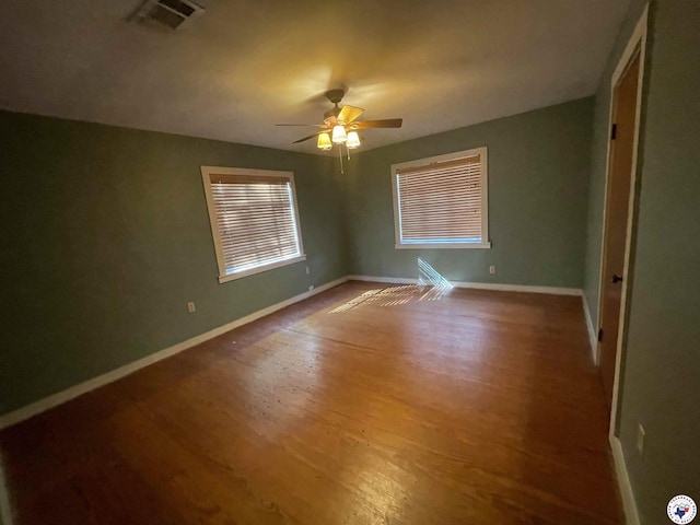 unfurnished room with baseboards, ceiling fan, wood finished floors, and visible vents