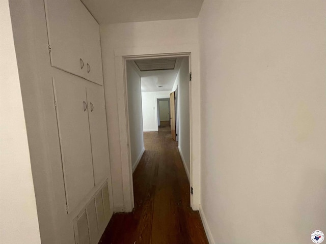 hallway with visible vents, dark wood-style flooring, and baseboards