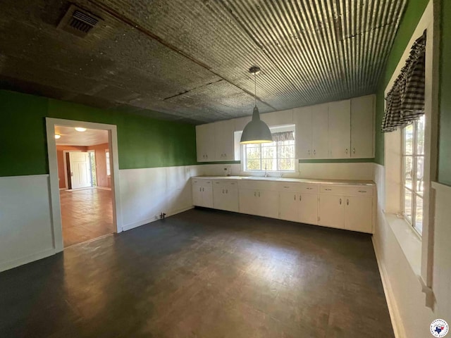 kitchen featuring white cabinets, hanging light fixtures, a sink, light countertops, and visible vents