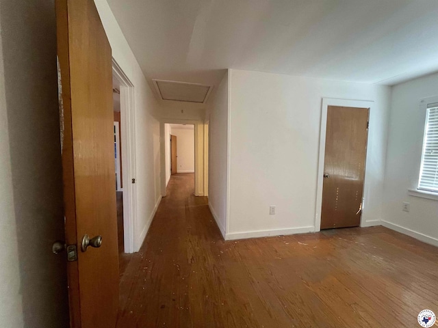 hallway with baseboards, attic access, and wood finished floors