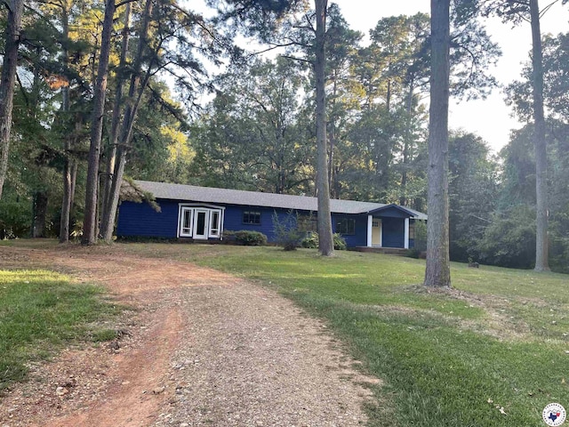 single story home featuring dirt driveway and a front lawn