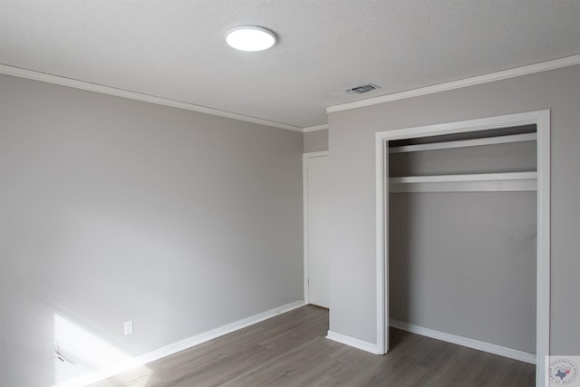 unfurnished bedroom with a closet, crown molding, dark hardwood / wood-style flooring, and a textured ceiling