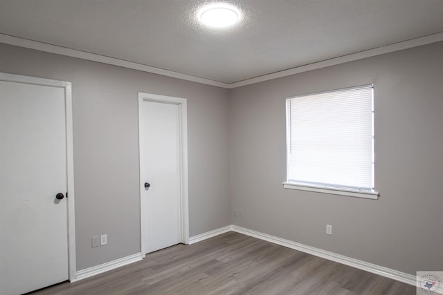 unfurnished bedroom featuring a textured ceiling, ornamental molding, and light wood-type flooring