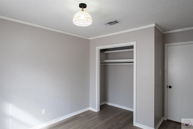 unfurnished bedroom featuring a closet, crown molding, dark wood-type flooring, and a textured ceiling