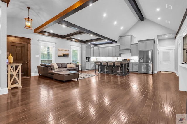 living room featuring sink, dark wood-type flooring, beam ceiling, high vaulted ceiling, and a notable chandelier