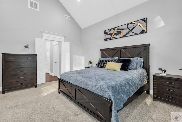 bedroom with high vaulted ceiling, ensuite bath, and light carpet