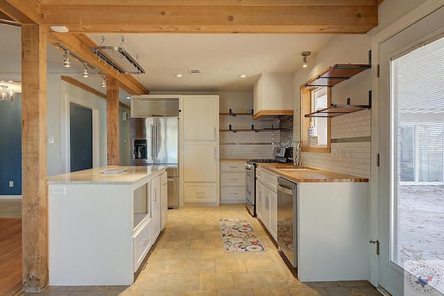 kitchen featuring decorative backsplash, a wealth of natural light, white cabinetry, and stainless steel appliances