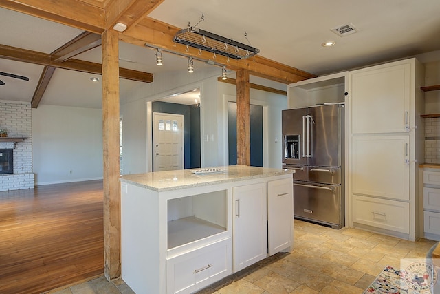 kitchen featuring white cabinets, high end refrigerator, a kitchen island, and light stone countertops