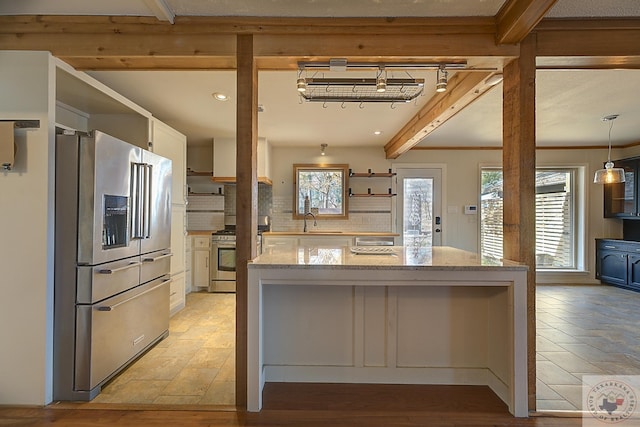 kitchen featuring light stone countertops, white cabinetry, sink, pendant lighting, and stainless steel appliances