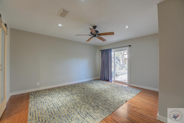 spare room with ceiling fan, hardwood / wood-style flooring, and a barn door